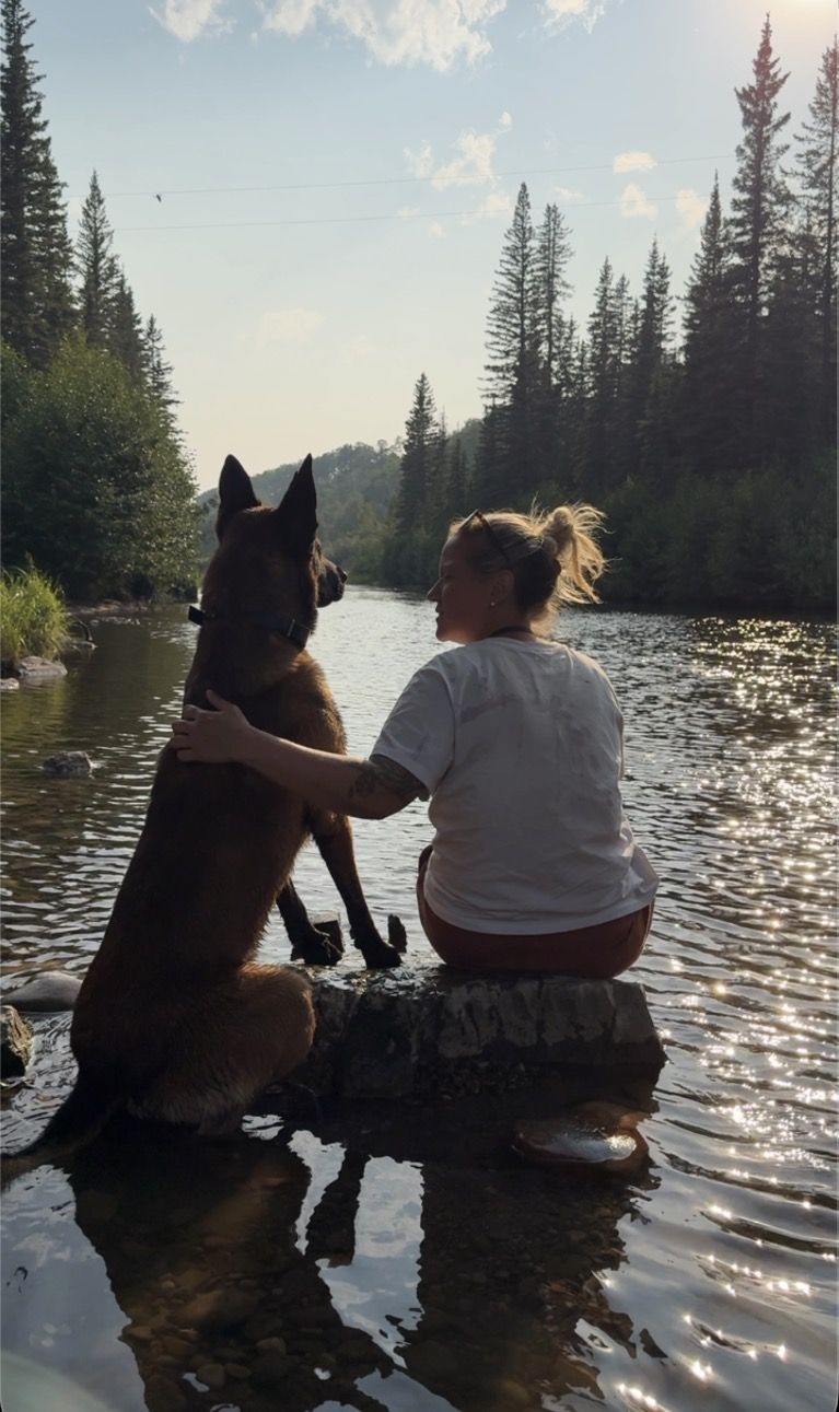 Dellie and Scout sitting in the river surrounded by pine trees